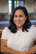 Black Shoulder Length Hair, Middle Eastern woman smiling, with a white short sleeve top 