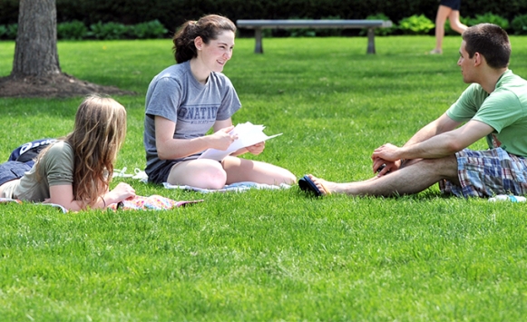 Three students studying on quad in spring