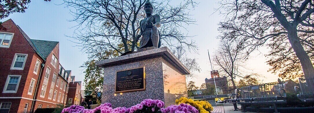 St Ignatius Statue at dusk with flowers in front of statue