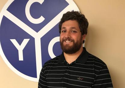Vince Minniti stands in front of a CYO logo